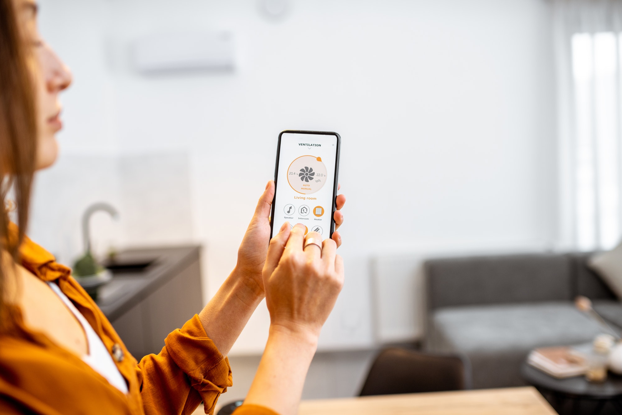 Woman controlling ventilation with a smart phone at home