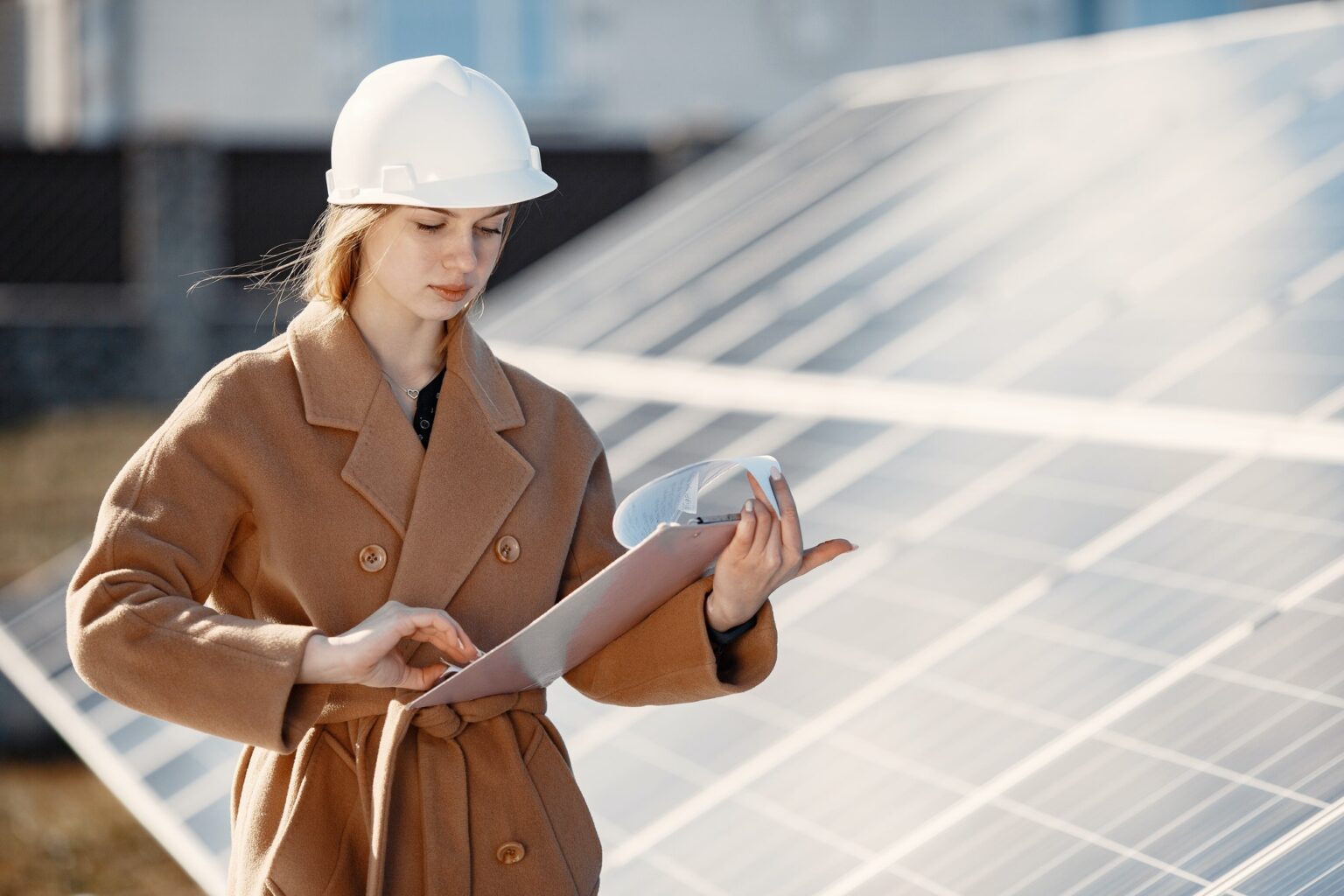 Young woman with checklist standing at solar plant